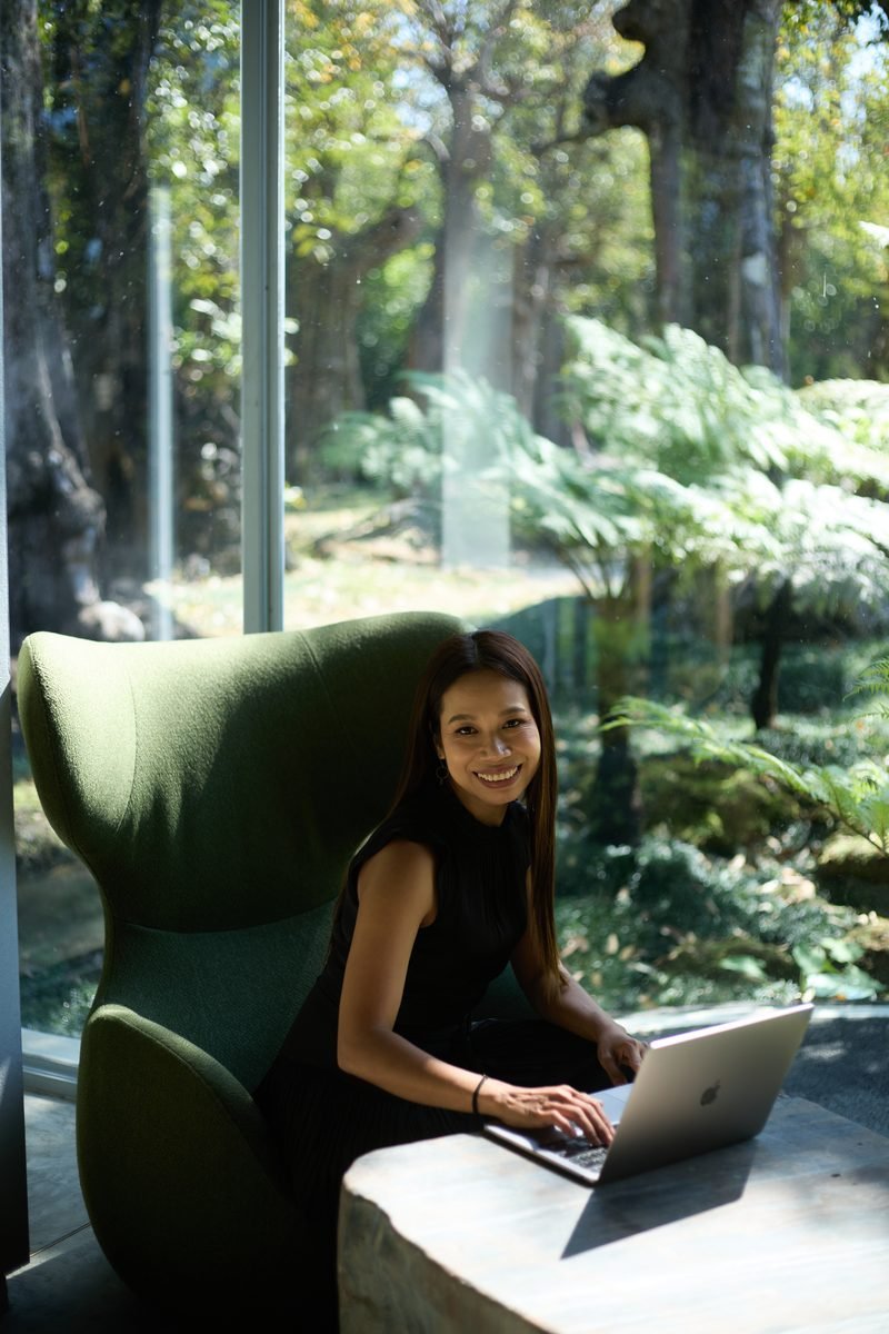 Fon Ward, SEO consultant for longevity clinics, working on a laptop in a green armchair